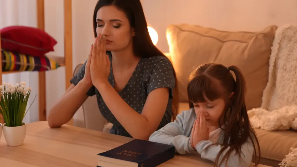 Mãe e filha unidas em oração em sala de estar, reforçando a proteção espiritual do lar com fé e amor 