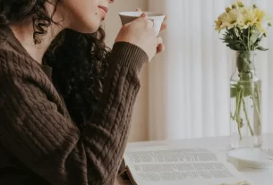 Mulher sorrindo enquanto segura uma xícara em uma manhã iluminada, representando uma rotina com propósito