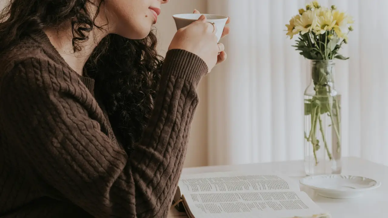 Mulher sorrindo enquanto segura uma xícara em uma manhã iluminada, representando uma rotina com propósito