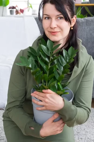 mulher com uma planta nas mãos demonstrando o poder das plantas na rotina da casa